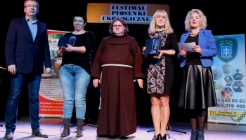 prezes spółki komunalnej, zastępca burmistrza i franciszanin na scenie wręczają nagrody