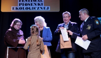 prezes spółki komunalnej, zastępca burmistrza i franciszanin na scenie wręczają nagrody