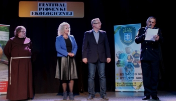 prezes spółki komunalnej, zastępca burmistrza i franciszanin na scenie wręczają nagrody