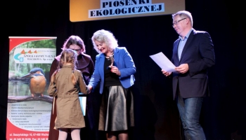 prezes spółki komunalnej, zastępca burmistrza i franciszanin na scenie wręczają nagrody