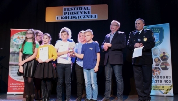 prezes spółki komunalnej, zastępca burmistrza i franciszanin na scenie wręczają nagrody