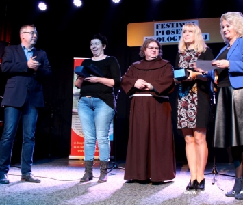 prezes spółki komunalnej, zastępca burmistrza i franciszanin na scenie wręczają nagrody