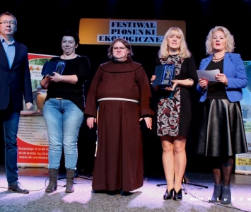 prezes spółki komunalnej, zastępca burmistrza i franciszanin na scenie wręczają nagrody