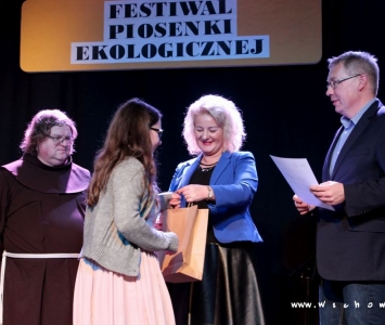 prezes spółki komunalnej, zastępca burmistrza i franciszanin na scenie wręczają nagrody