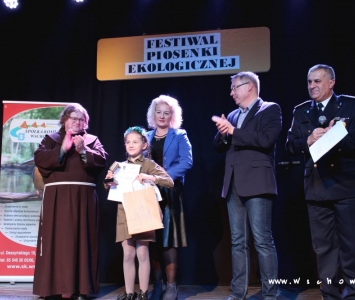 prezes spółki komunalnej, zastępca burmistrza i franciszanin na scenie wręczają nagrody