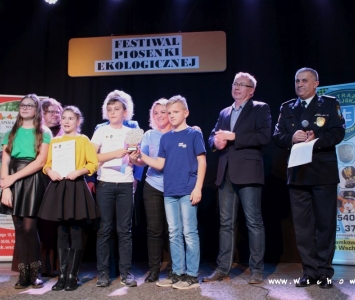 prezes spółki komunalnej, zastępca burmistrza i franciszanin na scenie wręczają nagrody